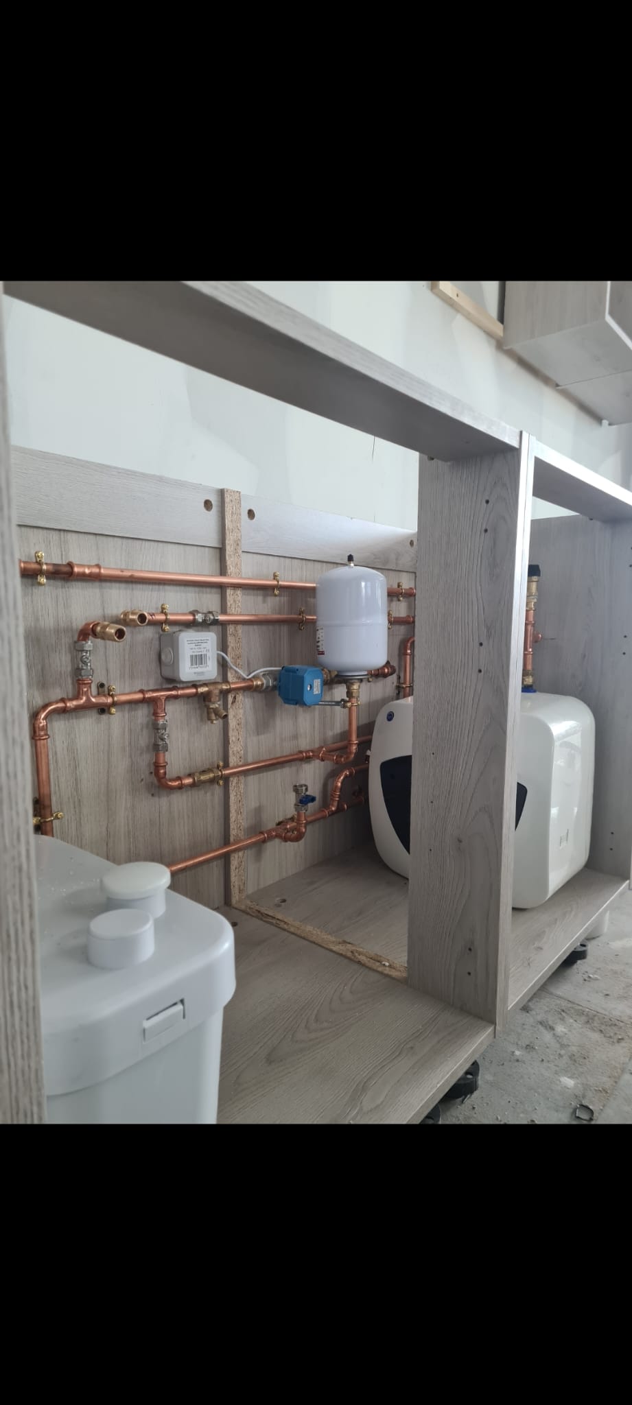 Copper pipework, expansion vessel and small water heater inside a service cabinet